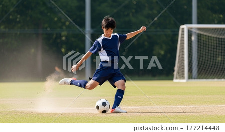 Male student kicking a soccer ball at a general sports tournament 127214448