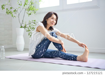 一位 50 多歲的女性穿著瑜伽服做瑜伽 一位 50 多歲的女性穿著瑜伽服做瑜伽 127215121