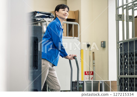 一名 50 多歲的女性在物流倉庫工作 一名 50 多歲的女性在物流倉庫工作 127215334