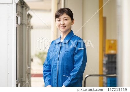 一名 50 多歲、身穿工作服的女性在倉庫工作 127215339
