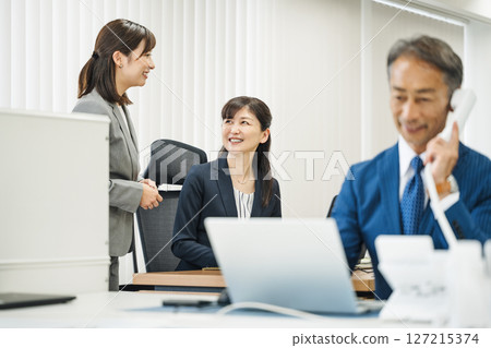 一位 50 多歲的職業婦女在辦公室與下屬交談 127215374