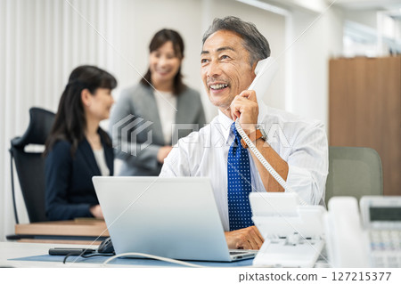 Senior male salesman making a phone call in the office 127215377