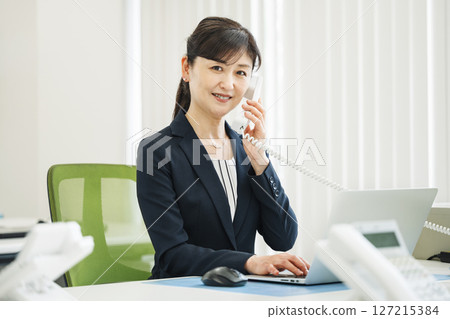 A career woman in her 50s making a phone call in the office A career woman in her 50s making a phone call in the office 127215384