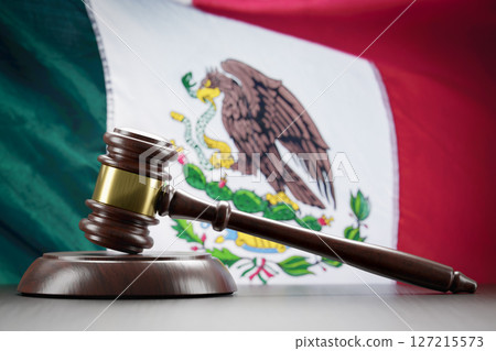 Wooden Gavel Resting on Table In Front of Mexican Flag 127215573