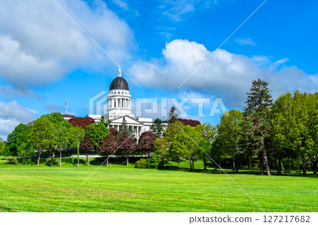 In Augusta, United States, the Maine State House dome peeks above leafy Capitol Park with a bright spring lawns under a vivid blue sky 127217682