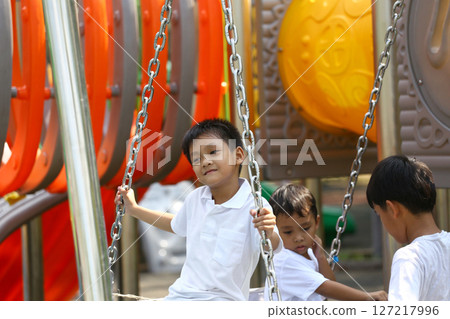 Joyful Children Playing on Swings at a Colorful Outdoor Playground, Enjoying a Sunny Day of Fun and Friendship in a Vibrant Environment with Play Equipment 127217996