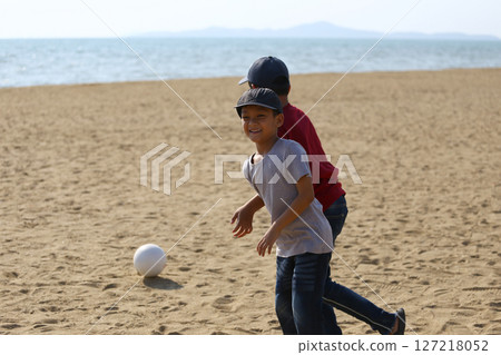 Joyful Children Playing Together on Beach During Sunny Day, Running and Smiling with a White Ball, Creating Fond Memories in a Relaxing Coastal Environment Joyful Children Playing Together on Beach During Sunny Day, Running and Smiling with a White Ball, Creating Fond Memories in a Relaxing Coastal Environment 127218052