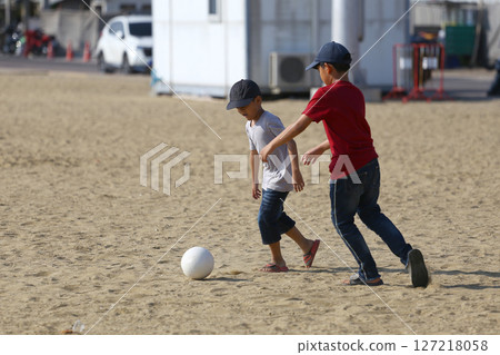 Two Young Children Play Together on a Sandy Beach with a White Ball, Engaging in Outdoor Activity and Enjoying a Sunny Day of Fun and Laughter Two Young Children Play Together on a Sandy Beach with a White Ball, Engaging in Outdoor Activity and Enjoying a Sunny Day of Fun and Laughter 127218058