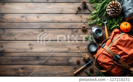 A wooden floor showcases a travel backpack and hiking equipment, ready for a camping trip or forest hiking adventure 127218231