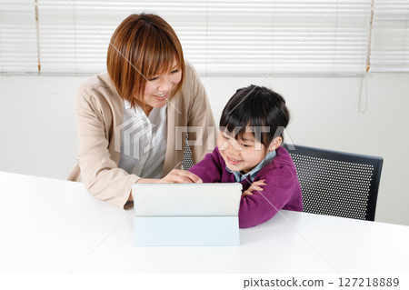 Elementary school children learning on a tablet and being taught by a female teacher Elementary school children learning on a tablet and being taught by a female teacher 127218889