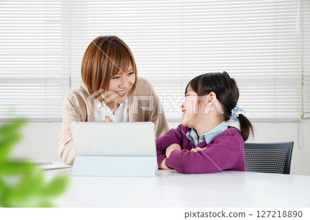 一個孩子很高興受到表揚，一位女士用平板電腦教他 127218890