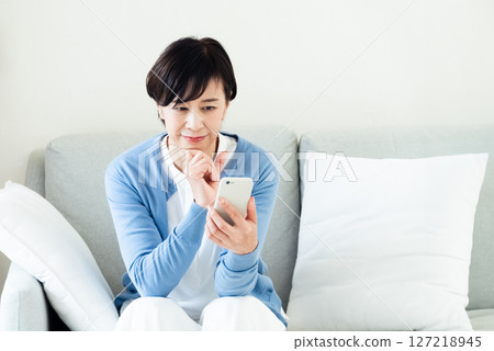 A middle-aged woman who operates a smartphone A middle-aged woman who operates a smartphone 127218945