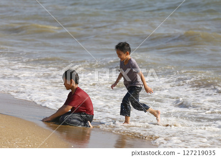 Joyful Children Enjoying a Day at the Beach, Playing in the Waves and Creating Happy Memories on a Sunny Summer Afternoon by the Shore 127219035
