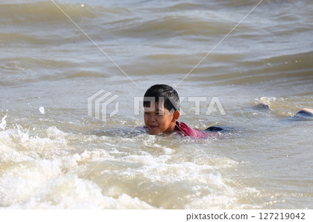 Boy Enjoys a Day Swimming in the Ocean Waves, Experiencing Joyful Moments of Adventure and Playfulness at the Beach During a Sunny Day 127219042