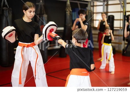 Teenage girl in boxing mitts trains with boy in boxing gloves Teenage girl in boxing mitts trains with boy in boxing gloves 127219059