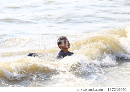 A Young Boy Enjoying a Swim in the Ocean Waves, Capturing the Joy and Freedom of Childhood on a Sunny Day at the Beach with Soft Sand and Gentle Surf A Young Boy Enjoying a Swim in the Ocean Waves, Capturing the Joy and Freedom of Childhood on a Sunny Day at the Beach with Soft Sand and Gentle Surf 127219061