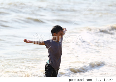 Joyful Child Playing at the Beach, Embracing Nature and Adventure with Open Arms, Capturing the Essence of Childhood Freedom in the Waves 127219062