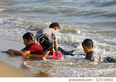 Young Children Playing in Shallow Water at the Beach, Enjoying Summer Fun with Sand and Waves, Full of Joy and Laughter on a Sunny Day 127219081