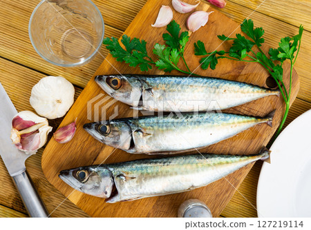 Delicious raw sardine with herbs on kitchen board closeup 127219114