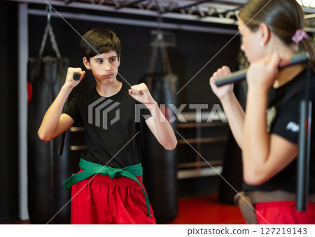 Teenage boy and girl training with nunchucks Teenage boy and girl training with nunchucks 127219143