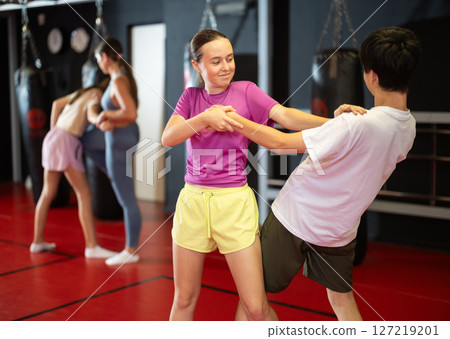 Teenage boy and girl practice self-defense in pairs 127219201