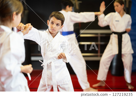 Boy and girl train to perform defensive karate installations and attacking combat techniques Boy and girl train to perform defensive karate installations and attacking combat techniques 127219235