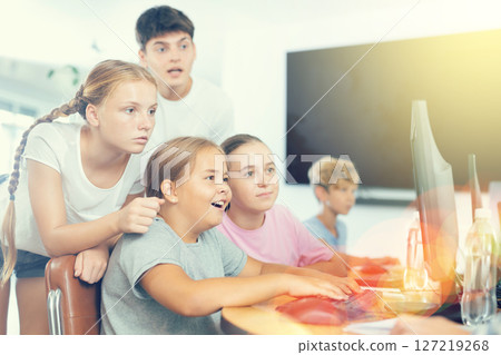 Preteen boys and girls working on computer together with teacher in IT cabinet 127219268