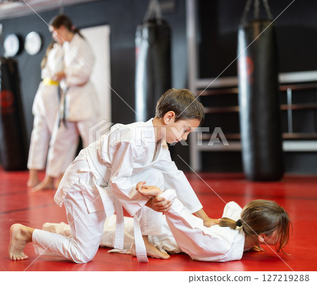 Children athletes in pair conduct training battle in oriental fighting technique Children athletes in pair conduct training battle in oriental fighting technique 127219288
