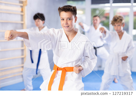 Preteen attendee of karate classes practicing kata standing in row with others Preteen attendee of karate classes practicing kata standing in row with others 127219317