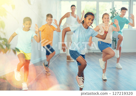 Active preteen children practicing Hip-hop dance with young trainer Active preteen children practicing Hip-hop dance with young trainer 127219320
