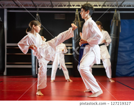 Boy and girl train to perform defensive karate installations and attacking combat techniques 127219327