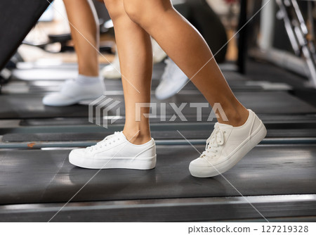 Feet of woman running on treadmill close-up 127219328