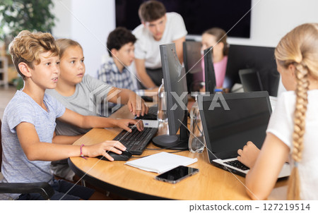 Computer science lesson in a school computer class - a girl and a boy solve problems on computer together 127219514