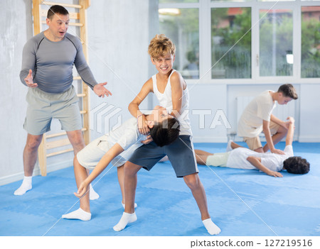 Teens applying inverted headlock in sparring during self-defense training 127219516