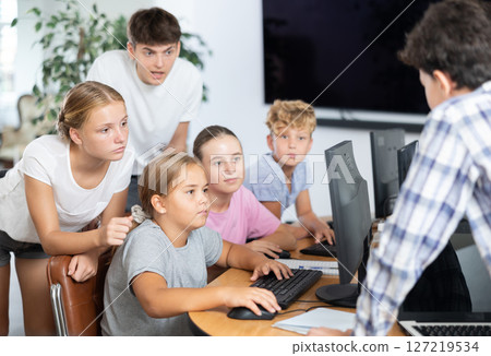 Computer lesson in classroom - classmates solve problems on computer together Computer lesson in classroom - classmates solve problems on computer together 127219534