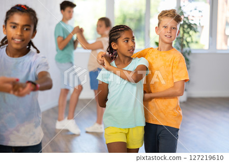Active preteen children practicing Ballroom dances in pairs in training hall 127219610