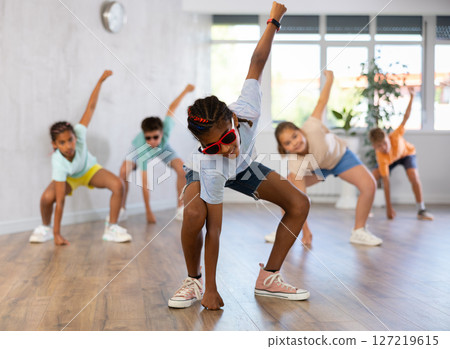 Preteenage boy and girl in sunglasses dancer practicing active dance in modern studio 127219615