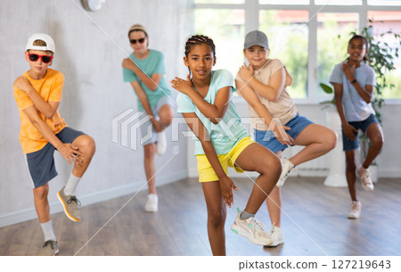 African girlie perform movements during warm-up with coeval in ball cap and dark glasses, 127219643