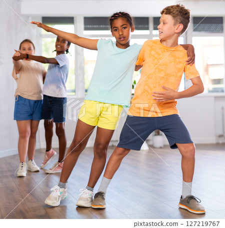 Active multinational children enjoying of partner dance in in dance studio Active multinational children enjoying of partner dance in in dance studio 127219767