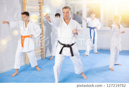 Karate instructor demonstrating kata sequence of movements to group of teenagers Karate instructor demonstrating kata sequence of movements to group of teenagers 127219782