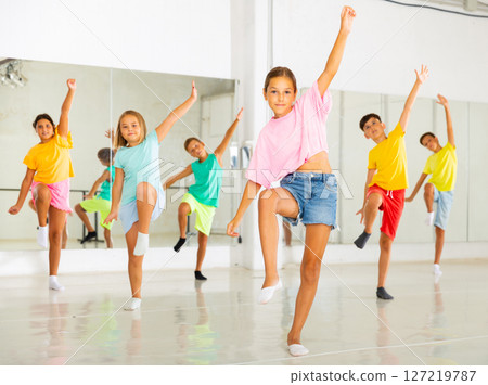 Kids warming up in group dance class, doing stretching exercises before dance 127219787