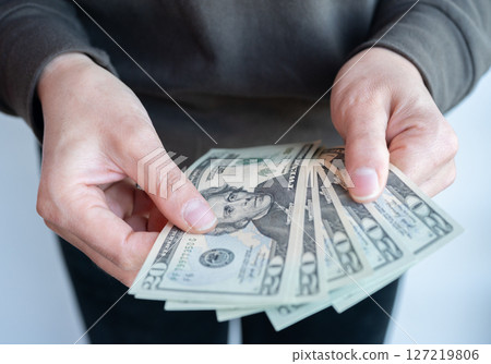 Cropped shot view of someone holding twenty American dollar banknotes in hands. The US Dollar is the currency of United States. 127219806