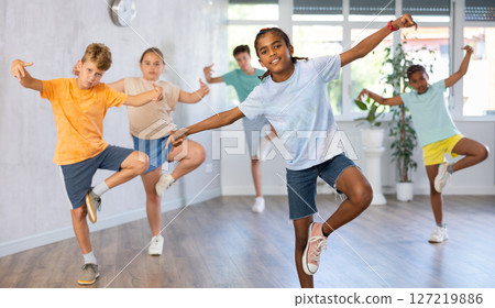 Girls and boys doing dance workout during group class in fitness center Girls and boys doing dance workout during group class in fitness center 127219886