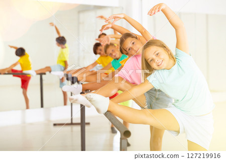 Group of children doing leg stretch at ballet barre Group of children doing leg stretch at ballet barre 127219916