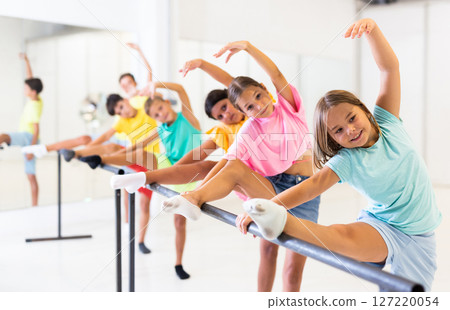 Group of children doing leg stretch at ballet barre Group of children doing leg stretch at ballet barre 127220054