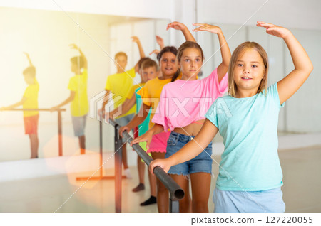 Preteen girls working near ballet barre during class Preteen girls working near ballet barre during class 127220055