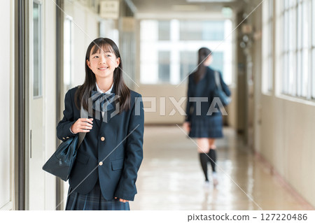 Female students, elementary school students, junior high school students, and high school students in uniform walking down a school corridor 127220486
