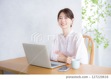 Smiling woman looking at camera in front of a computer Office casual image Cute woman in pink sheer shirt 127220616