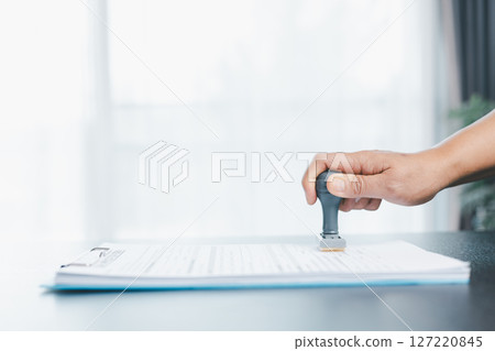 Businessman hands stamp approve on financial business approval document paper. Man hand accepted permit contract agreement. Broker manager sign contract bank guarantee approved stamp application form 127220845