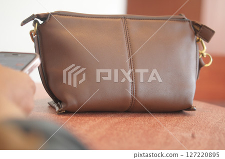 An Elegant Brown Leather Handbag is beautifully placed on a Table An Elegant Brown Leather Handbag is beautifully placed on a Table 127220895